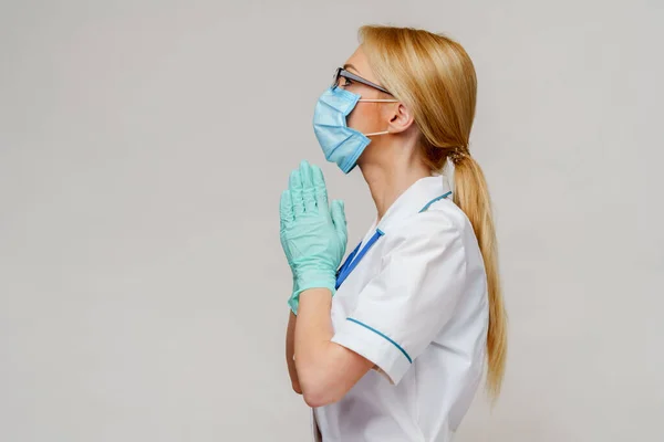 Médico médico enfermera mujer usando máscara protectora y guantes de látex - rezando nad esperando gesto —  Fotos de Stock