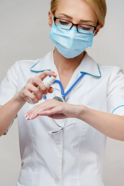 Medische arts verpleegkundige dragen beschermende masker - Holding fles van ontsmetten spray of gel — Stockfoto
