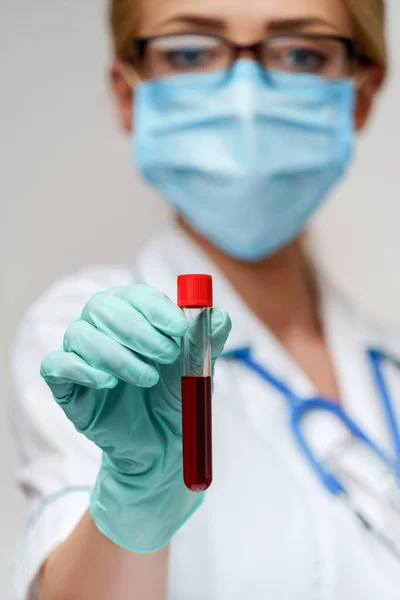 Medico infermiere donna indossando maschera protettiva e guanti - tenendo virus tubo di prova del sangue — Foto Stock