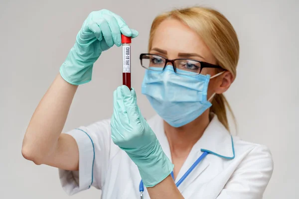 Médico enfermera mujer con máscara protectora y guantes - sosteniendo el tubo de análisis de sangre del virus — Foto de Stock