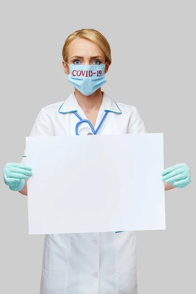 Medico infermiere donna indossando maschera protettiva e guanti - mostrando segno bianco — Foto Stock
