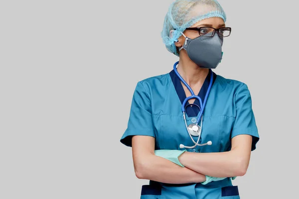 Steteskoplu kadın doktor koruyucu maske takıyor ve açık gri arka plan üzerine lateks eldiven takıyor. — Stok fotoğraf