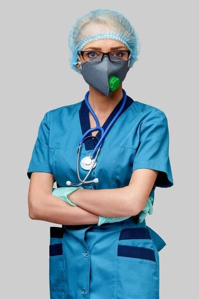 Médico feminino com estetoscópio vestindo máscara protetora e luvas de látex sobre fundo cinza claro — Fotografia de Stock