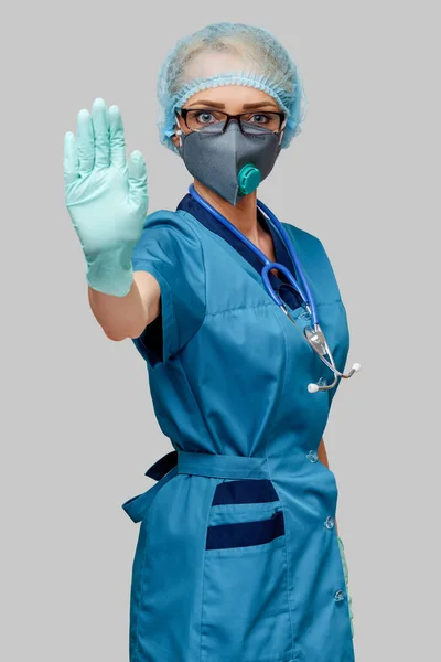 Vrouwelijke arts met stethoscoop dragen beschermende masker en latex handschoenen over lichtgrijze achtergrond — Stockfoto