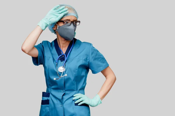 Γυναίκα γιατρός με στηθοσκόπιο φορώντας προστατευτική μάσκα και γάντια λάτεξ σε ανοιχτό γκρι φόντο — Φωτογραφία Αρχείου