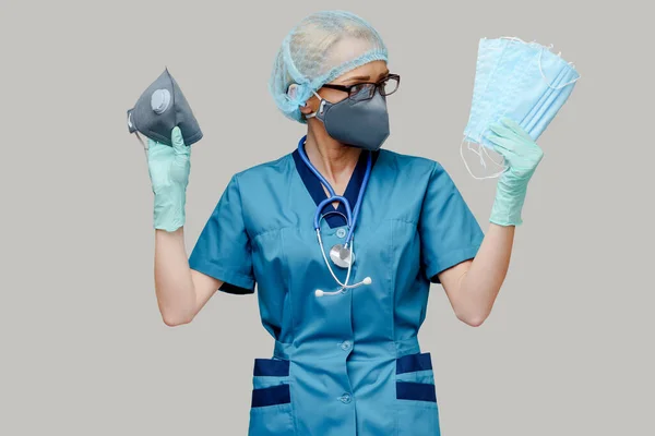 Femme médecin avec stéthoscope portant un masque protecteur et des gants en latex sur fond gris clair — Photo