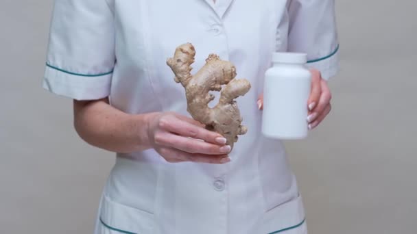 Nutritionist doctor healthy lifestyle concept - holding ginger root and jar of or vitamine pills — Stock Video