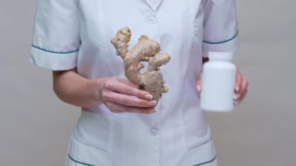 Nutritionist doctor healthy lifestyle concept - holding ginger root and jar of or vitamine pills — Stock Video