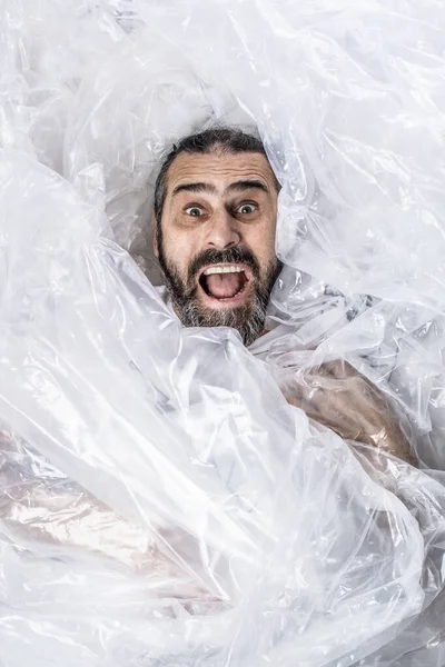 Retrato de um homem barbudo envolto em invólucro de plástico . — Fotografia de Stock