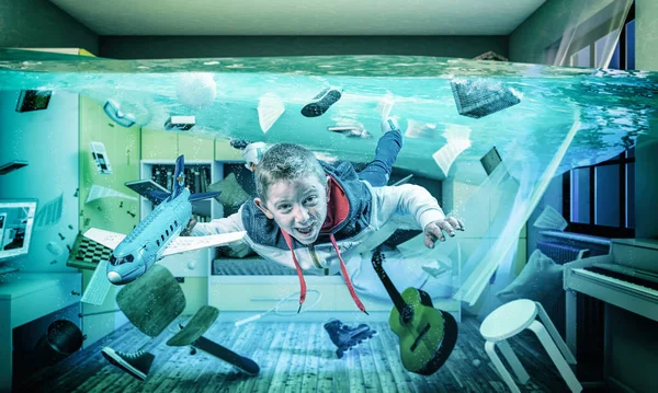 Το παιδί παίζει χαρούμενο με ένα αεροπλάνο στο πλημμυρισμένο δωμάτιό του.. — Φωτογραφία Αρχείου