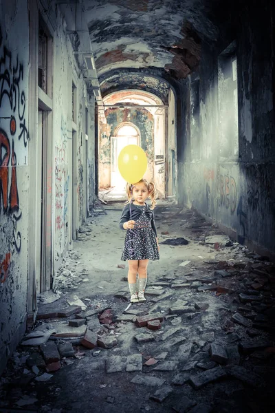 blonde girl with a balloon inside a decadent and abandoned build