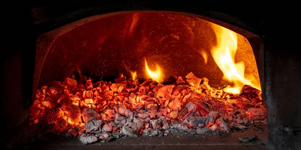 wood embers inside a wood-burning oven for the preparation of classic Italian pizza.