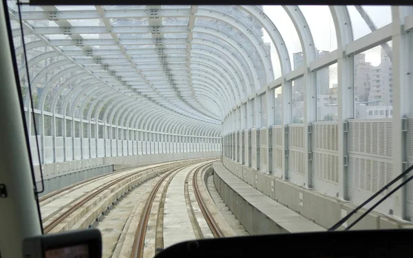 Een tram beweegt stations op een overdekte track Stockafbeelding
