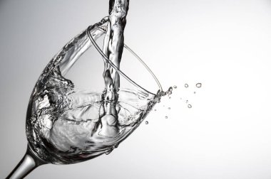 Su bardağı gri arka plan üzerinde dökme yakın çekim