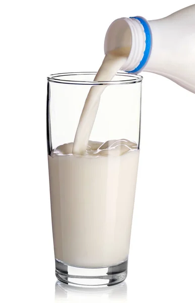 Пластиковая бутылка наливает молоко в стакан на белом фоне — стоковое фото