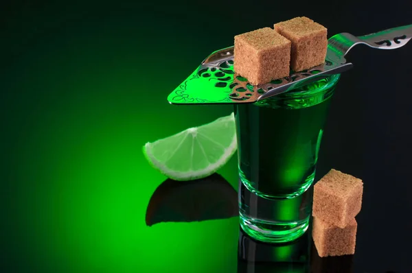 Absinthe shots with lime slices and sugar on dark green backgrou — Stock Photo, Image