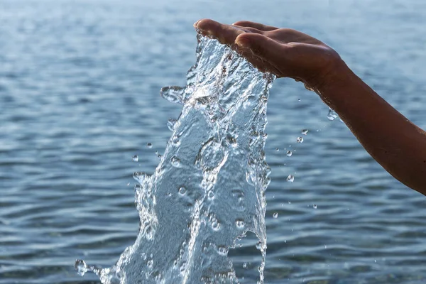 Espalhando água do mar e mão humana . — Fotografia de Stock