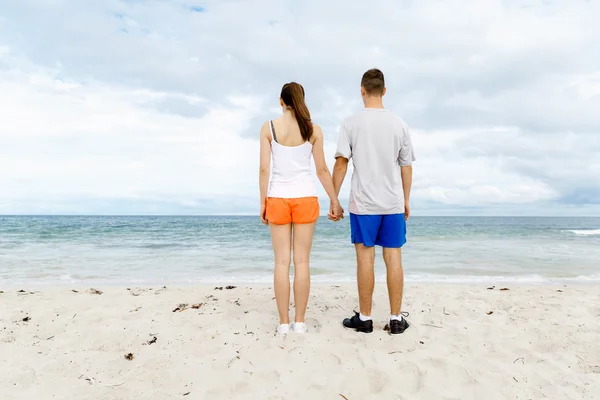 Jong koppel op zoek doordachte terwijl staande naast elkaar op het strand — Stockfoto