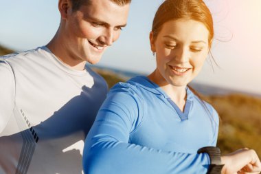 Kalp atış hızı monitörünü plajda çalışan kadınla Runner