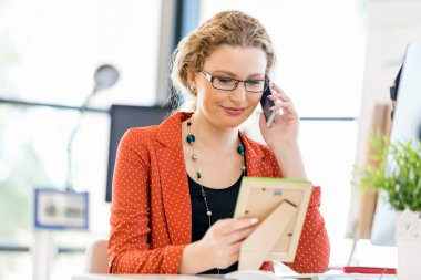 Ofiste bir fotoğraf çerçevesi tutan genç kadın