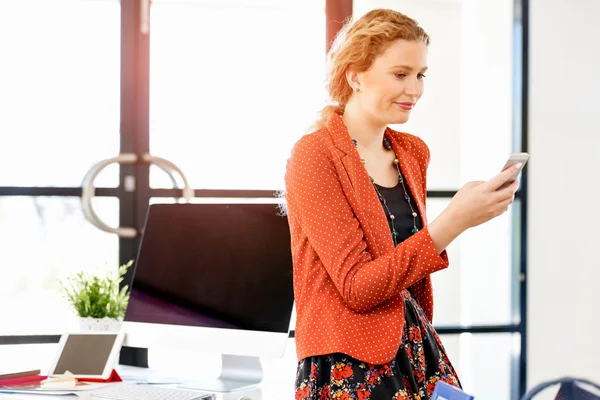 Young woman in office with mobile phone — Stock Photo, Image