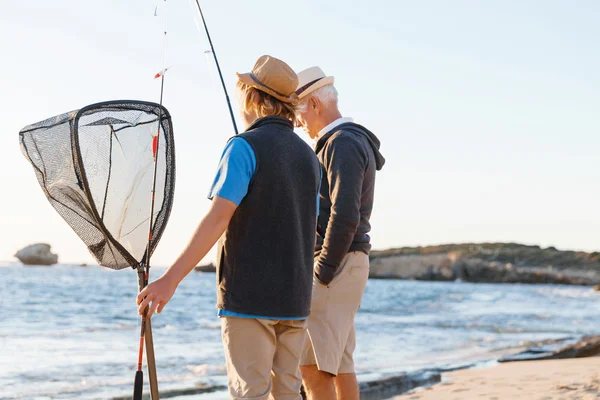 Hombre mayor pescando con su nieto — Foto de Stock