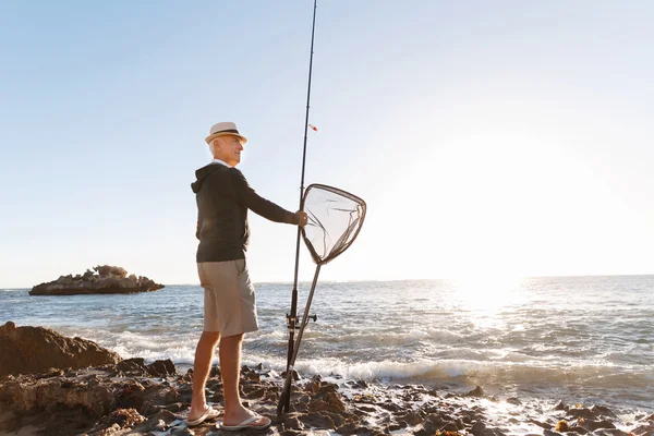 Starší muž rybolov na moři strana — Stock fotografie