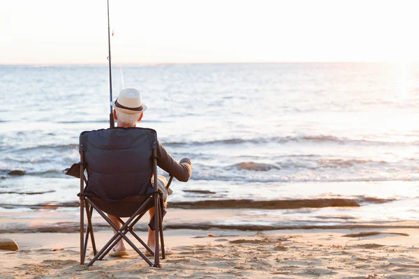 Senior man fishing at sea side — Stock Photo, Image