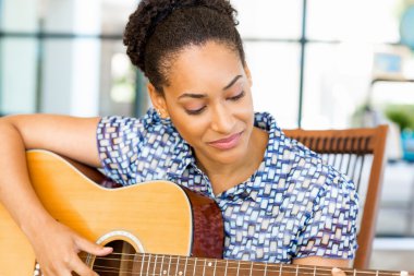 Gitar ile iş içinde oturan Afro-Amerikan ofis çalışanı gülümseyen portresi