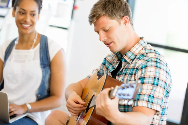 Estudantes sentados no chão com uma guitarra tocando — Fotografia de Stock