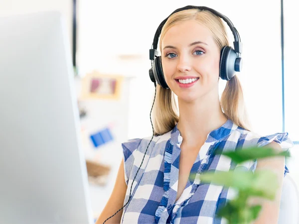 Junge Frau arbeitet im Büro mit Kopfhörern — Stockfoto