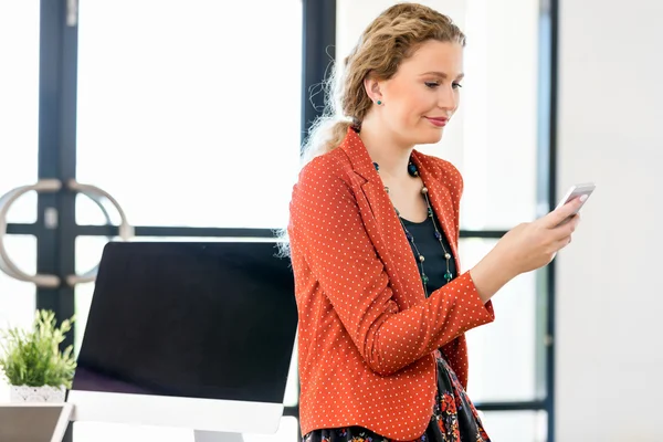 Jeune femme tenant un téléphone portable au bureau — Photo