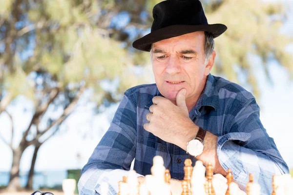 Homme assis à l'extérieur avec des échecs — Photo