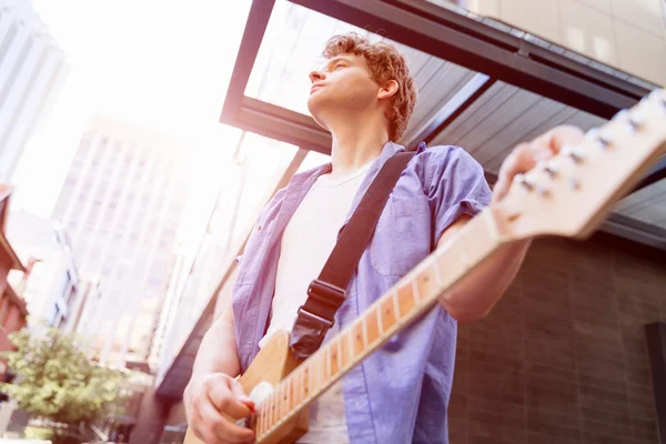 Mladý hudebník s kytarou v městě — Stock fotografie
