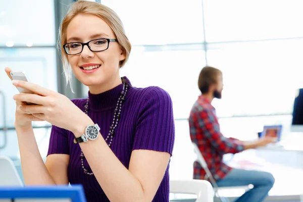 Zakenvrouw in kantoor houden van mobiele telefoon — Stockfoto