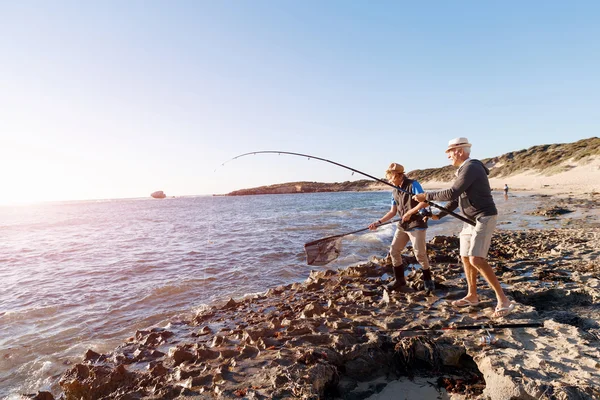 Uomo anziano pesca con suo nipote — Foto Stock