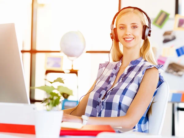 Mujer joven escuchando la música mientras trabaja en una computadora —  Fotos de Stock