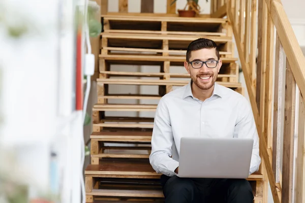 Portret van de jonge man zit bij de trappen in kantoor — Stockfoto