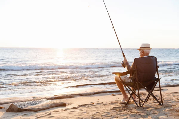 Senior man fishing at sea side — Stock Photo, Image