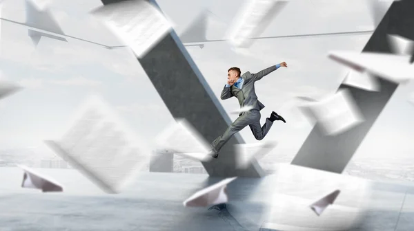 Jumping businessman in office . Mixed media — Stock Photo, Image