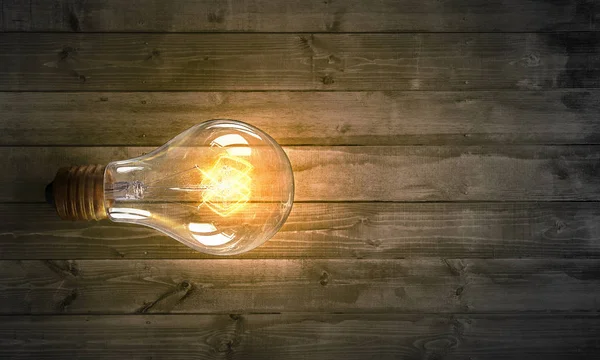 Glühbirne auf Holzoberfläche. Gemischte Medien — Stockfoto