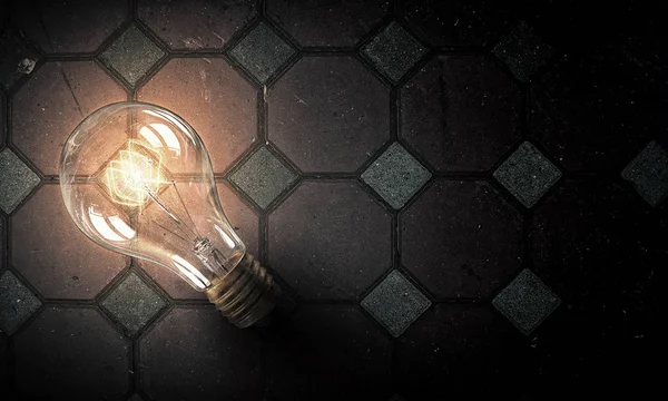 Light bulb on brick surface . Mixed media — Stock Photo, Image