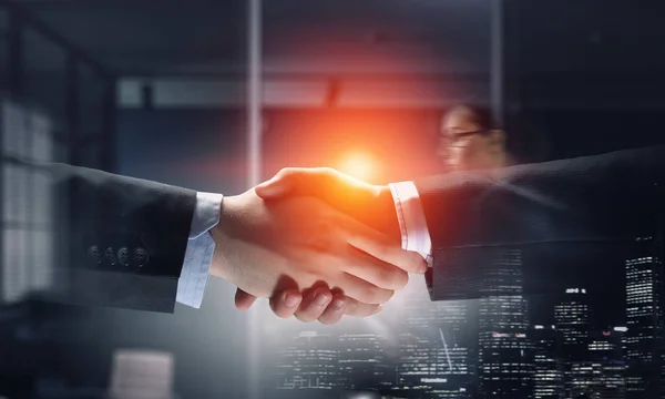 Partners shaking hands as symbol of deal . Mixed media — Stock Photo, Image