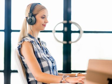 Kulaklıklar ile ofiste çalışan genç kadın