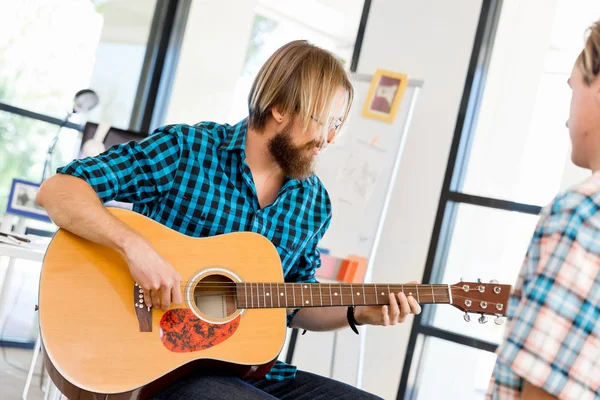 Uomo che suona la chitarra in ufficio — Foto Stock