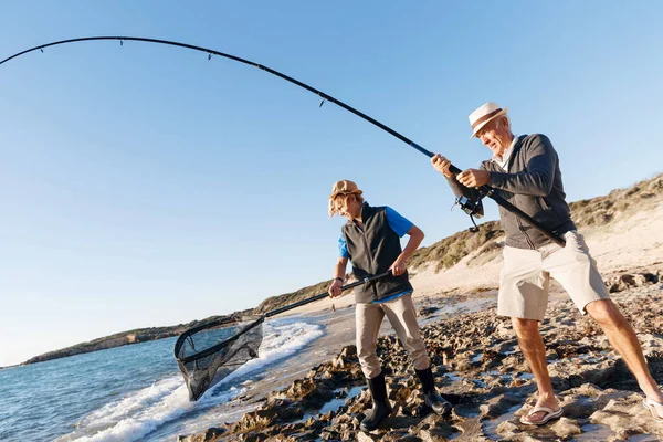 Hombre mayor pescando con su nieto — Foto de Stock