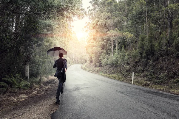 Bakifrån av affärsman med paraply och resväska gick på vägen — Stockfoto