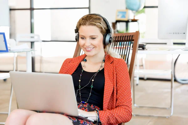 Junge Frau hört Musik, während sie am Computer arbeitet — Stockfoto