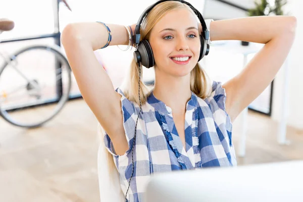 Молодая женщина слушает музыку во время работы за компьютером — стоковое фото