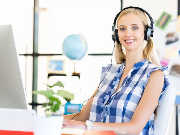 Junge Frau arbeitet im Büro mit Kopfhörern — Stockfoto